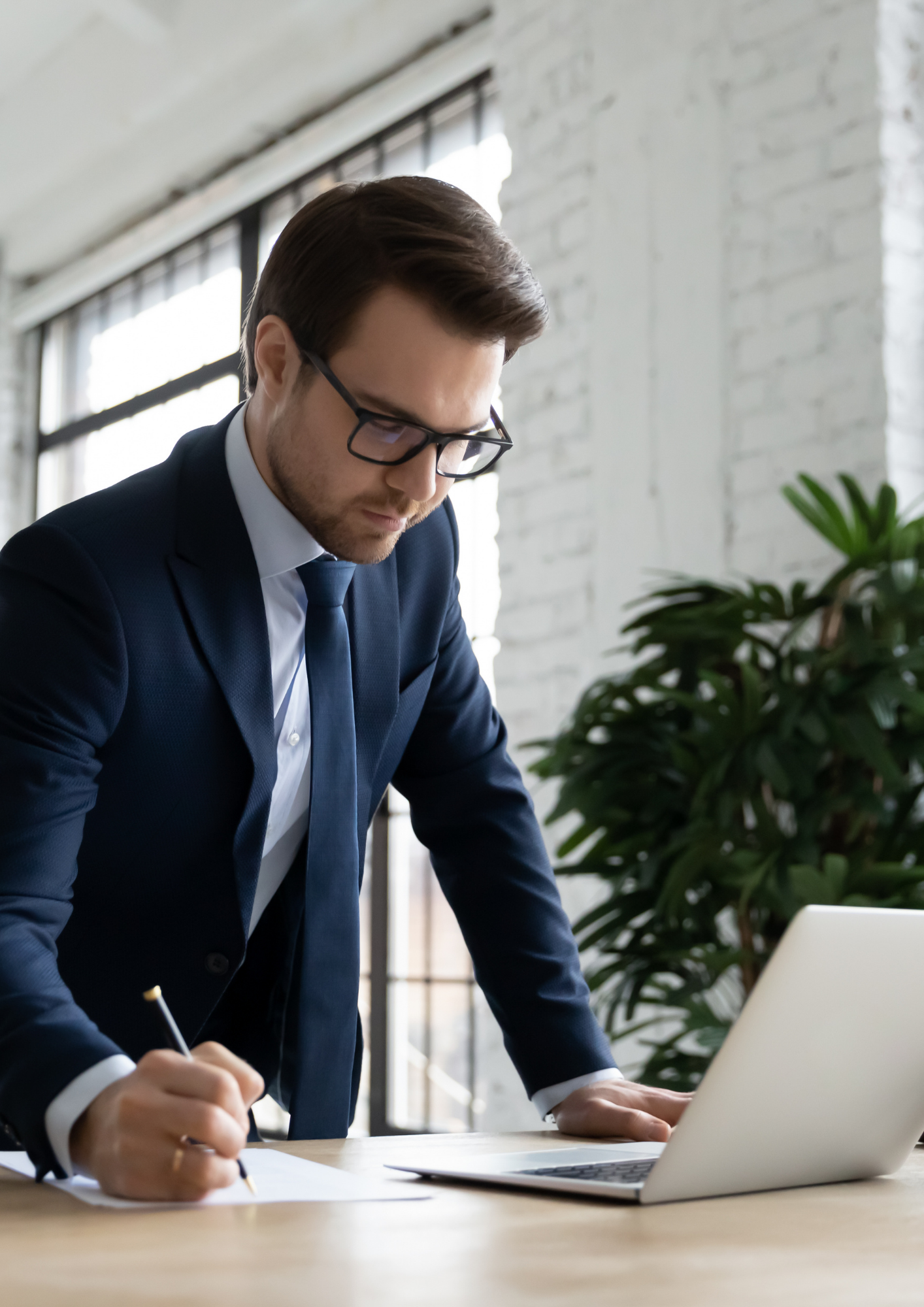 Business man leaning over laptop in smart attire