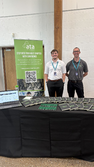 Two people standing in front of an ATA Recruitment Forces banner at a recruitment event, engaging with visitors about career opportunities for ex forces professionals.