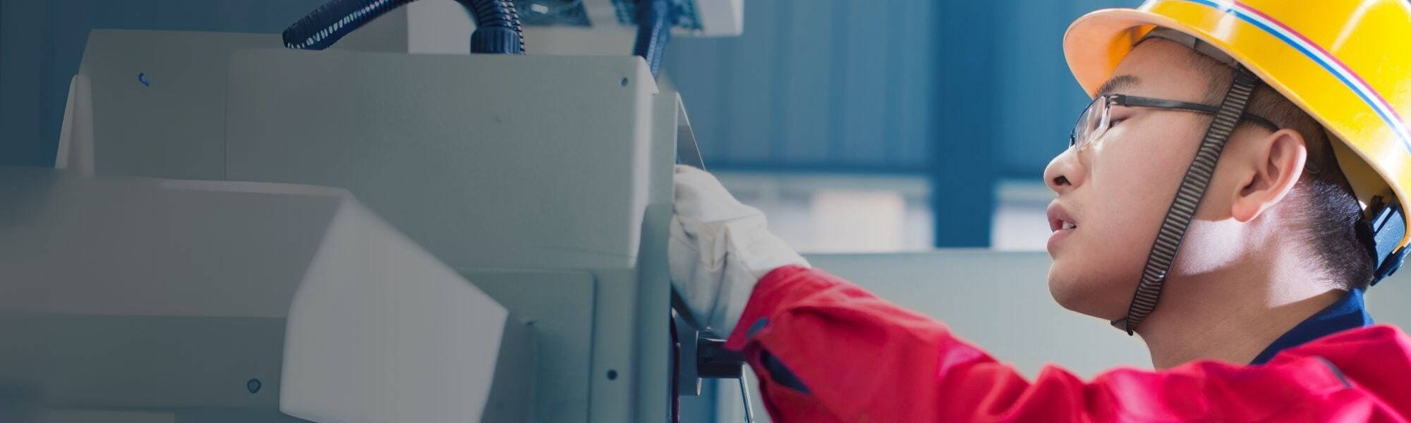 Maintenance engineer in safety gear inspecting industrial equipment in a factory setting