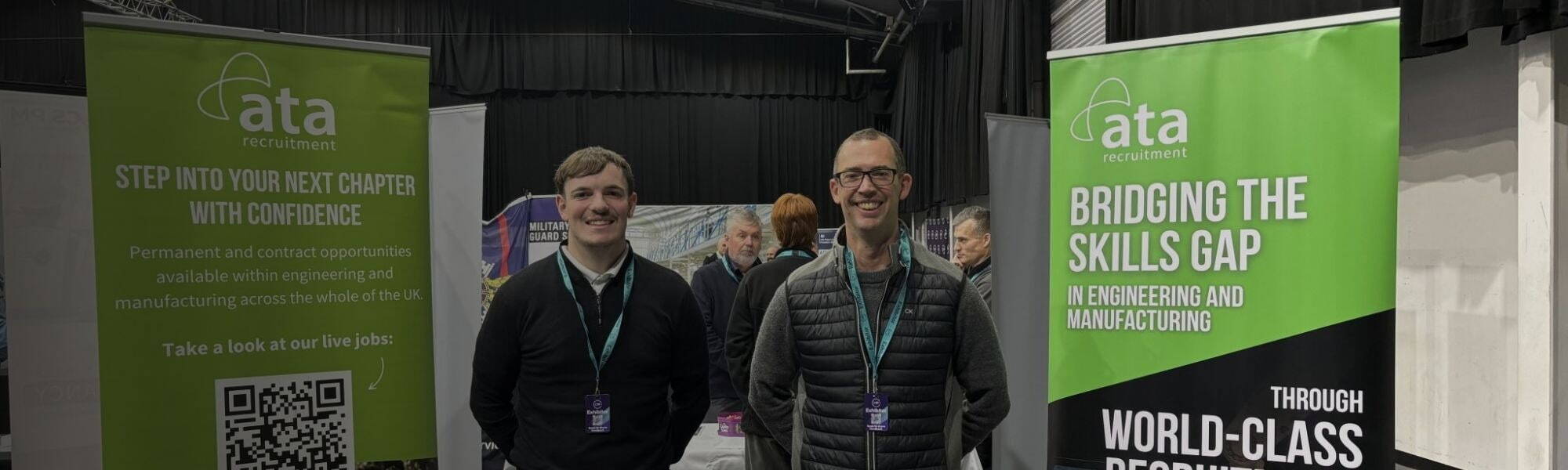 Chris and Lewis standing by table and our Bridging the skills gap banners