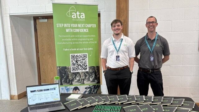 Two people standing in front of an ATA Recruitment Forces banner at a recruitment event, engaging with visitors about career opportunities for ex forces professionals.